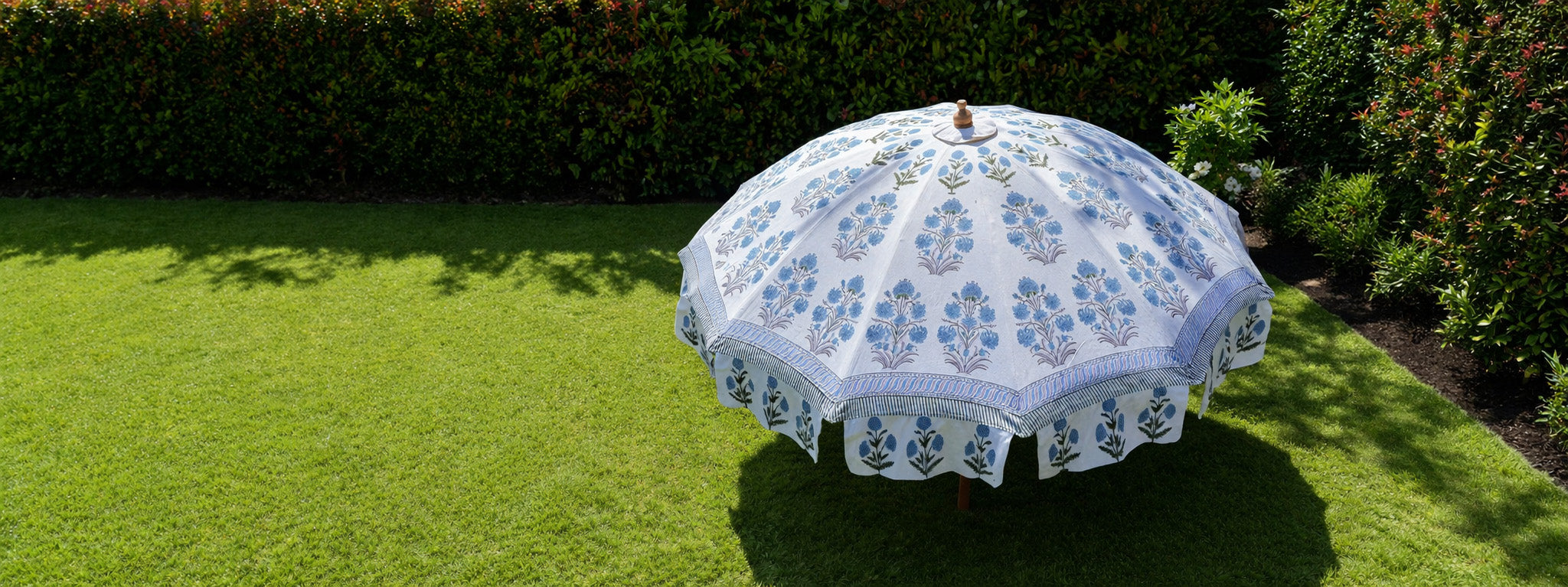 Decorative garden umbrella with floral pattern on a grassy lawn